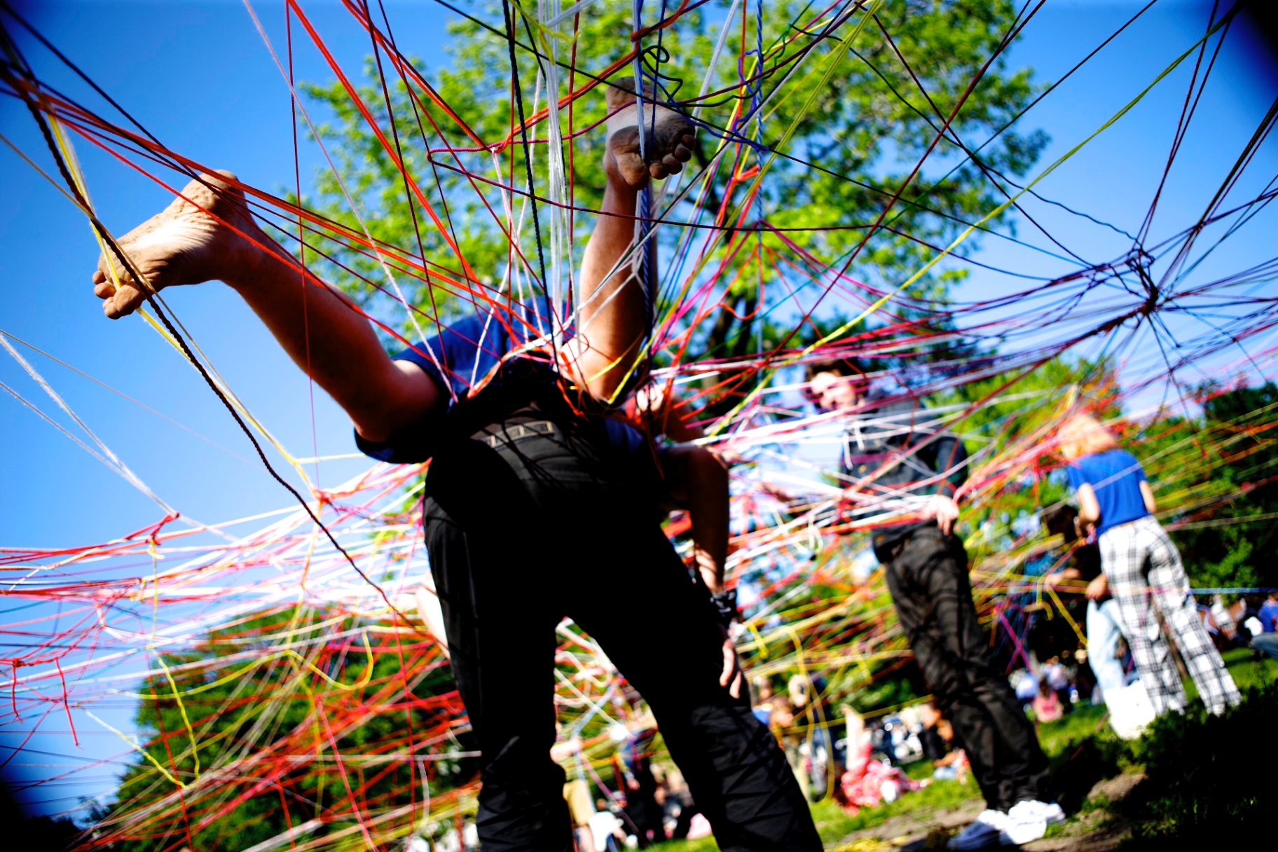 Person suspended and tangled in a dense web of primary-colored strings